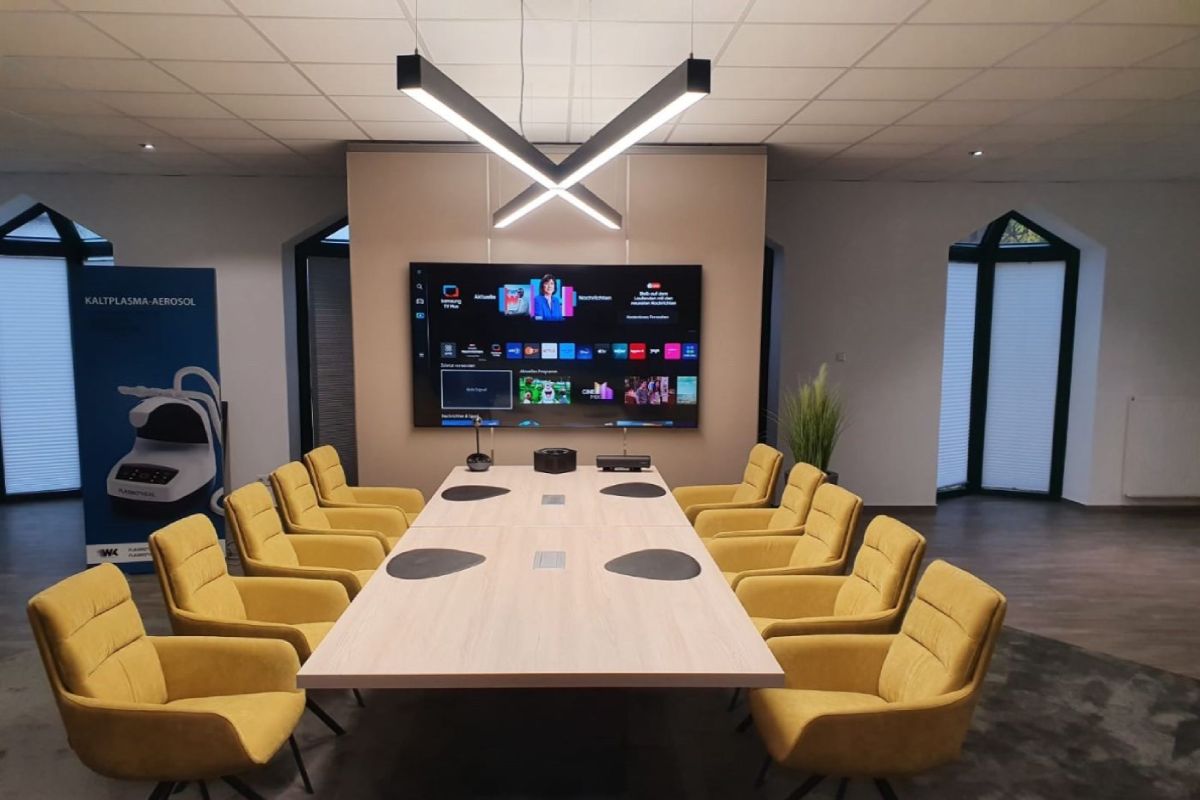 Custom X-shaped LED pendant light in a modern meeting room